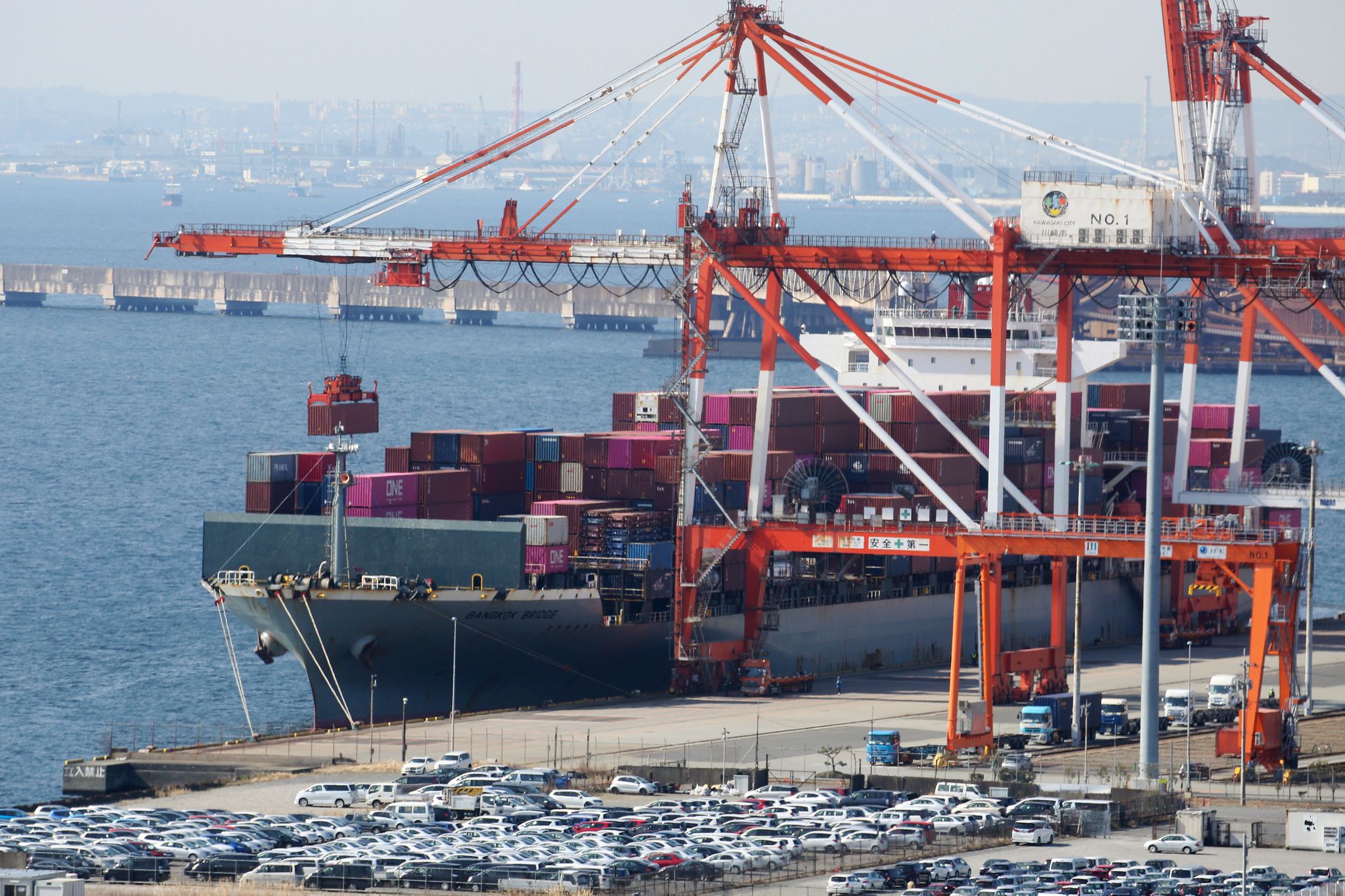Cargo ship loaded with electronics docking at Japanese port, overlaid with fluctuating yen currency charts and JPYC stablecoin logo, symbolizing hedging strategy against yen volatility for exporters